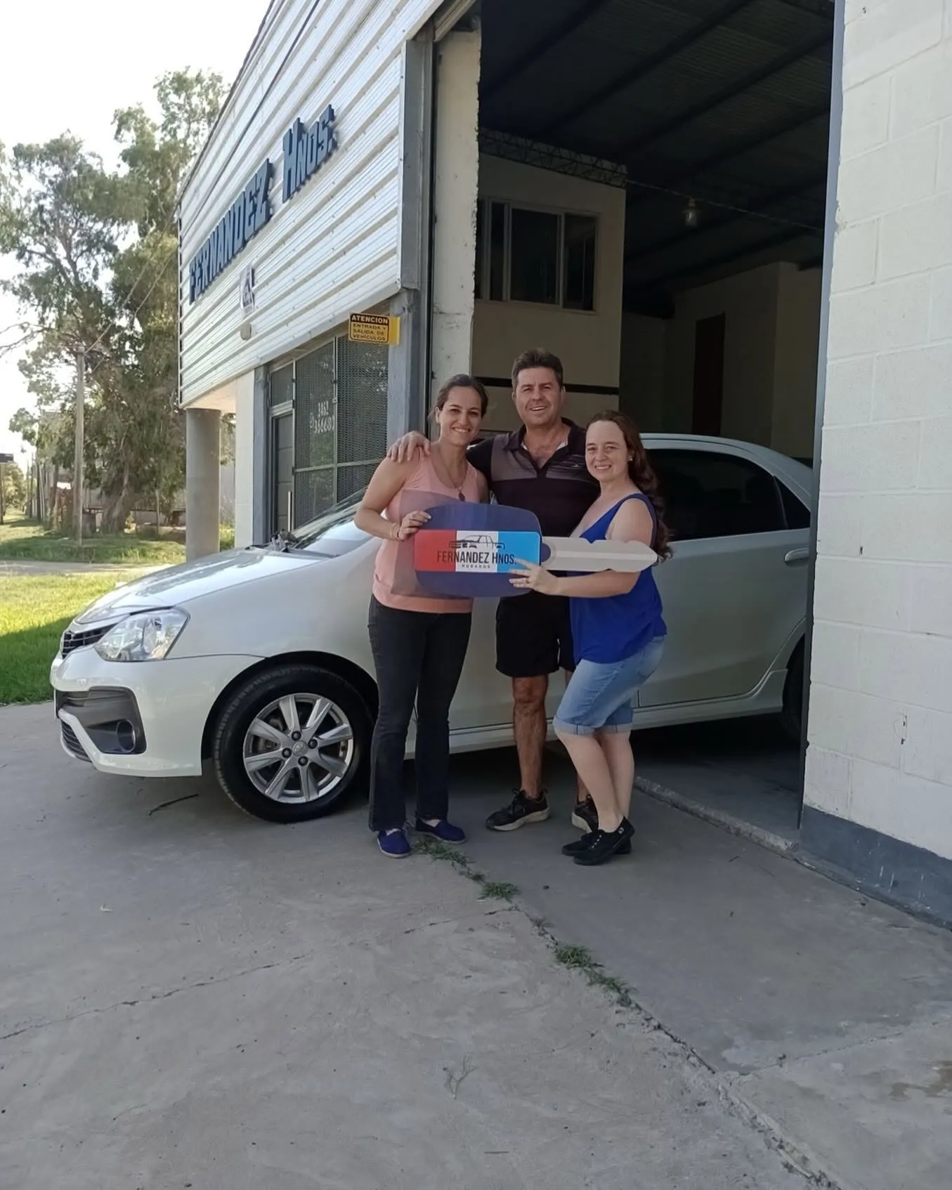 Clientes recibiendo su Toyota Etios con la llave gigante de Fernandez Hnos.